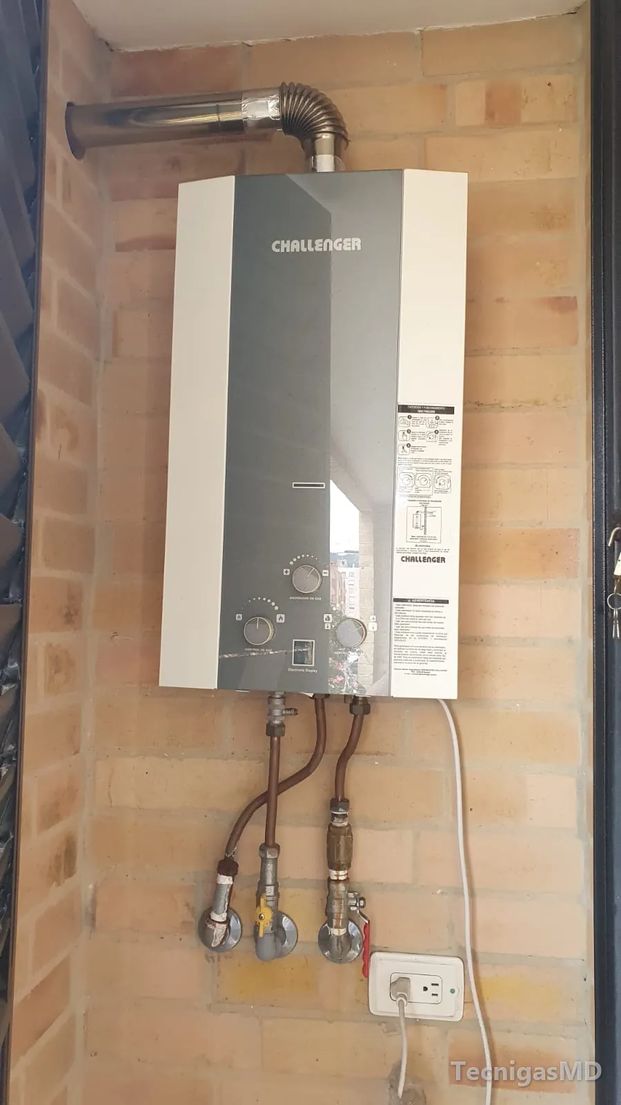 Calentador a gas de paso Challenger en muro de ladrillo, con ducto de evacuación, conexiones flexibles y válvulas de corte
