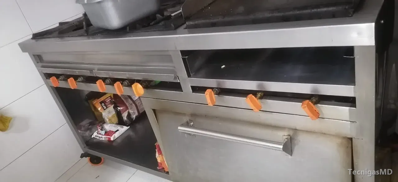 Estufa industrial a gas de acero inoxidable con quemadores, hilera de perillas naranjas, horno y repisa inferior en cocina