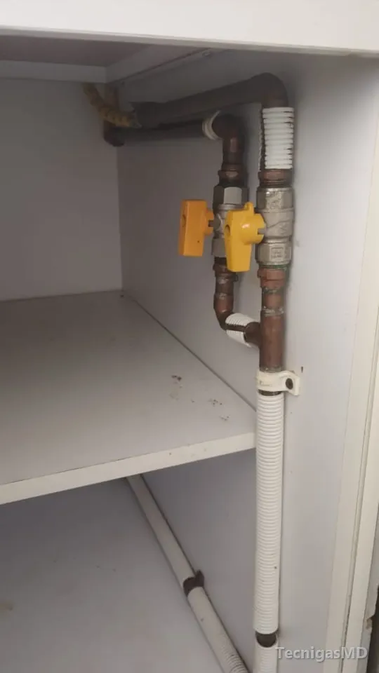 Derivación en tubería de cobre con dos válvulas de corte de manija amarilla, instalada dentro de un mueble blanco