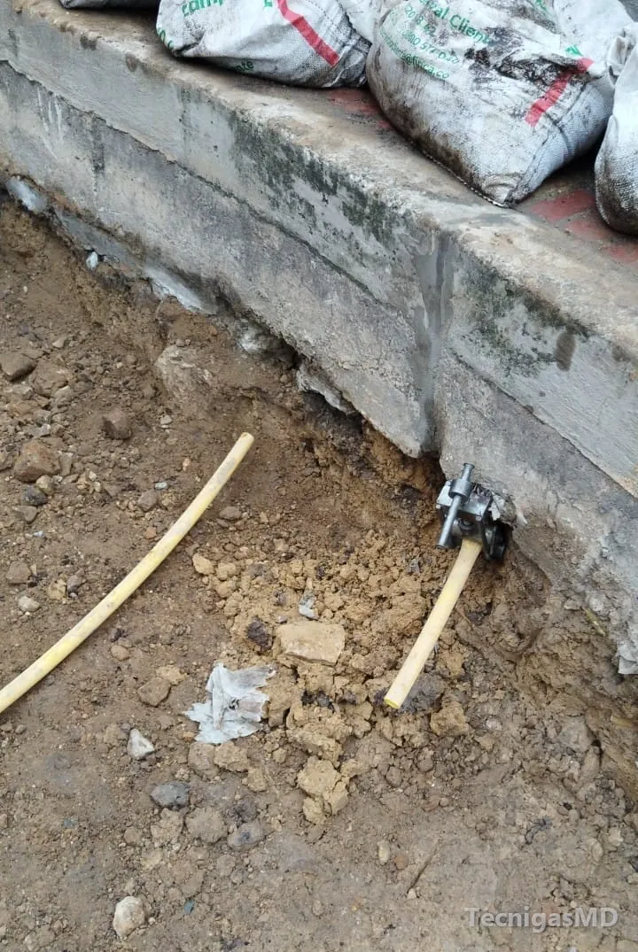 Zanja abierta al pie de un bordillo de concreto con la tubería amarilla de polietileno de la acometida de gas