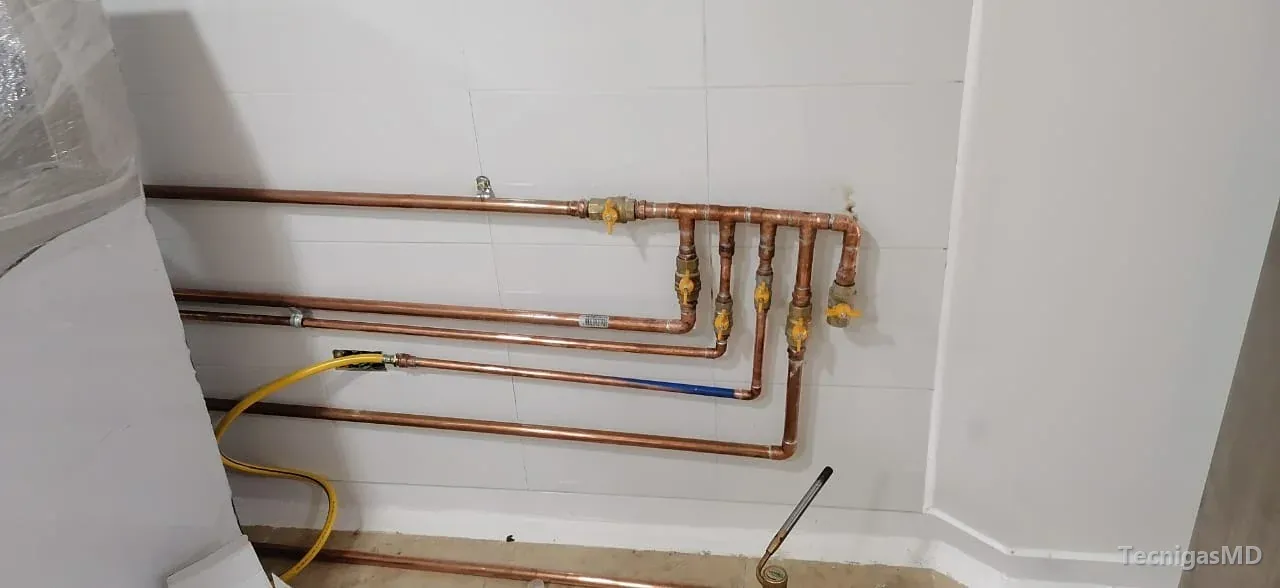 Tubería de cobre de red interna de gas sobre muro enchapado, con válvula general y colector de cinco salidas con válvula