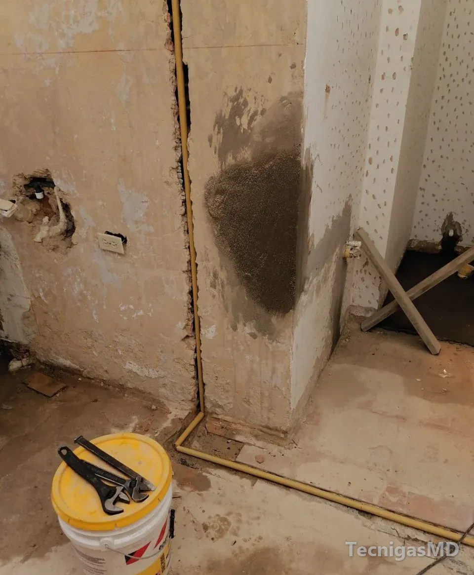 Tubería amarilla de gas que baja por una regata vertical del muro y sigue a ras del piso, en un espacio en remodelación